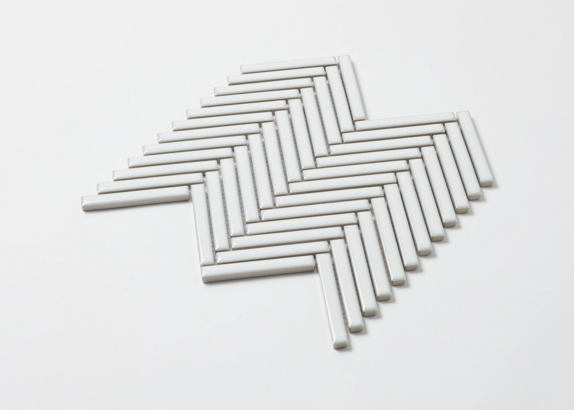 Pack shot of Antique White Gloss Porcelain Glazed Herringbone KitKat 12x92mm tiles arranged in a classic herringbone mosaic pattern on a white background.