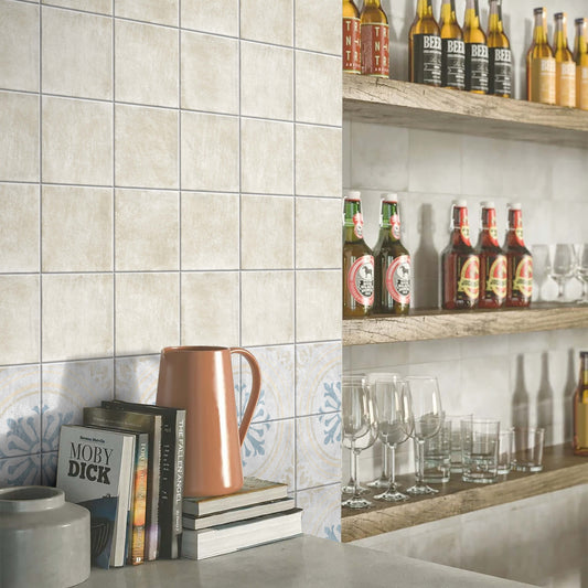 Antiquity Almond 150x150mm ceramic wall tiles installed in a bar setting with decorative patterned border tiles, wooden shelving, and glassware.
