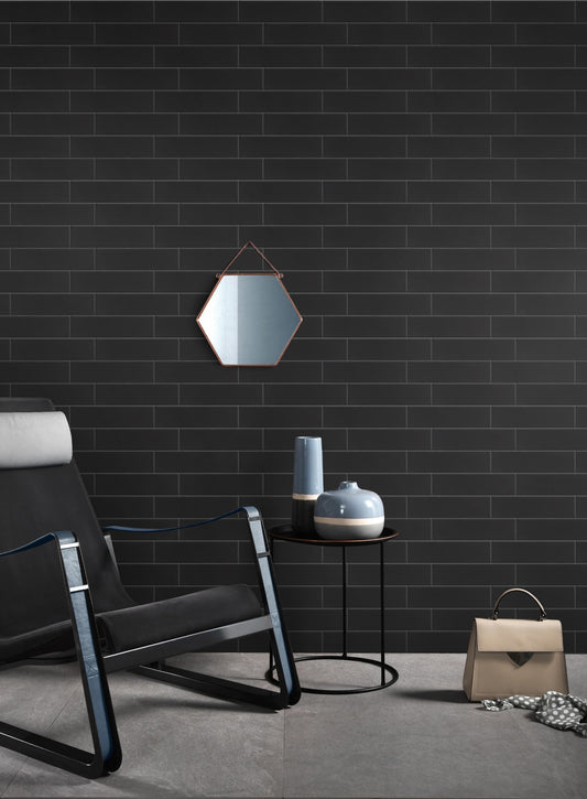 Aquarella Black Gloss 75x300mm tiles covering a dramatic dark feature wall styled with a modern lounge chair, hexagonal copper mirror, and ceramic vases.