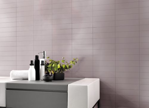 Aquarella Lilac Matt 75x300mm tiles installed as a full bathroom wall behind a modern grey vanity unit with soap dispensers and a potted plant.