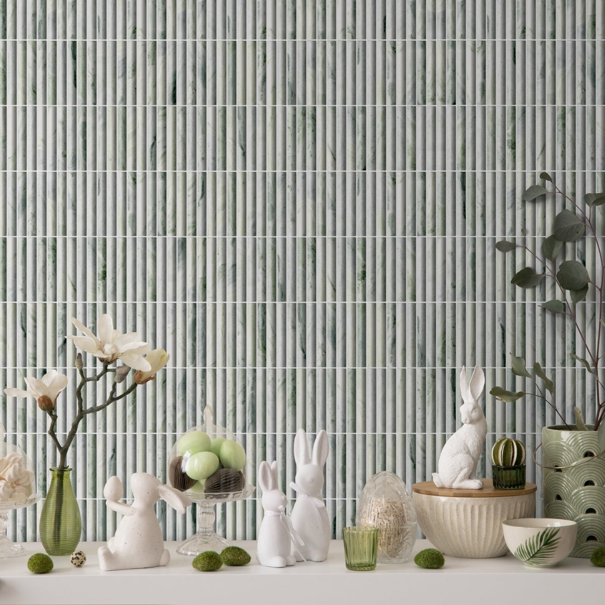 Archistone Calacatta Gold Mix Recycled Glass Matt Fluted 290x299mm styled as a feature wall backdrop behind a decorative Easter shelf display with white ceramic bunny figurines and green vases.