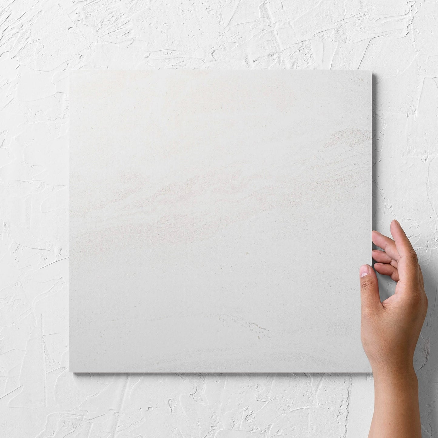 Hand holding a single Argyle Stone Talco 300x300mm tile against a white rendered wall, showing the tile surface
