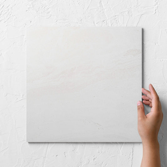Hand holding a single Argyle Stone Talco 300x300mm tile against a white rendered wall, showing the tile surface