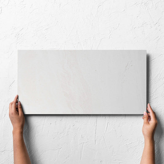 Hand holding a single Argyle Stone Talco Lappato 300x600mm tile against a white rendered wall, showing the tile surface