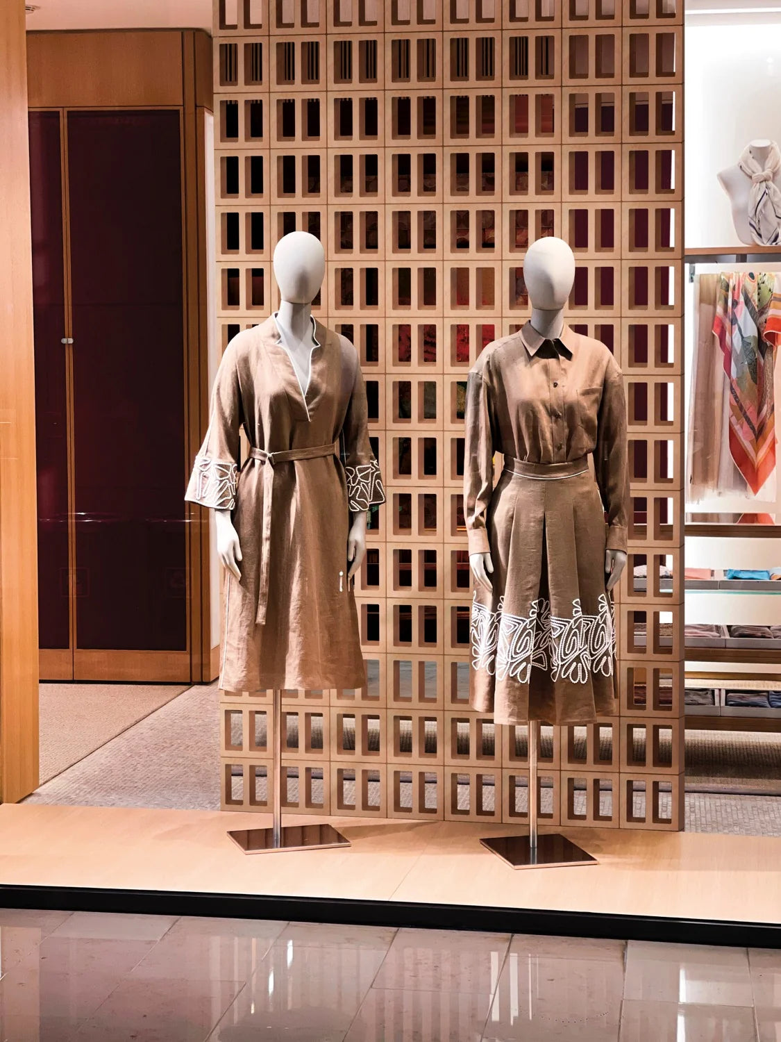 Artigianale Ombra Breeze Blocks 150x150mm featured as a warm timber-toned geometric screen wall in a luxury retail boutique display with fashion mannequins.