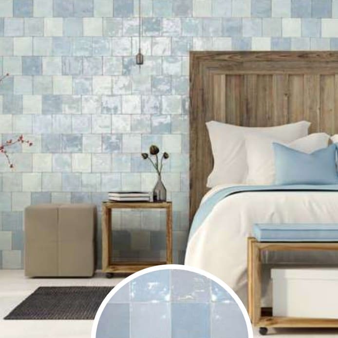 Artisan Azul Matte 130x130mm tiles covering a full bedroom feature wall in soft blue tones, styled with a rustic wooden bed frame and pendant light.