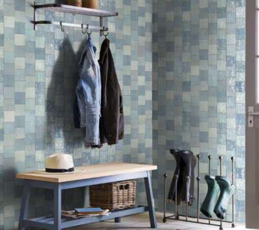 Artisan Azul Matte 130x130mm tiles covering an entryway mudroom wall in soft blue hues, styled with a coat rack, wooden bench, and wellington boot stand.