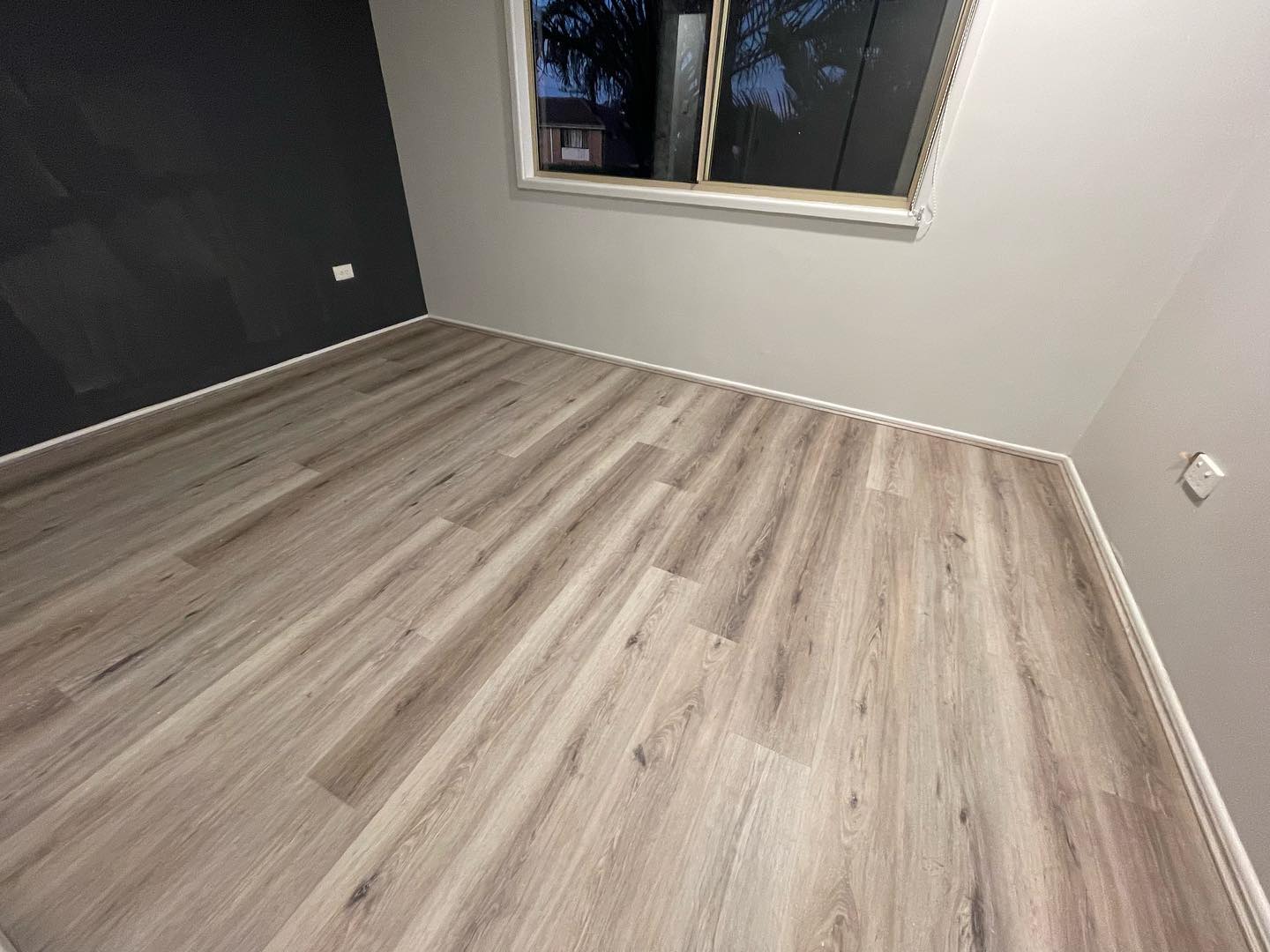 Ash Cliff Elegant SPC Hybrid 6.5mm Flooring 5+1.5mm installed in an empty bedroom with grey walls, a window, and white skirting boards.
