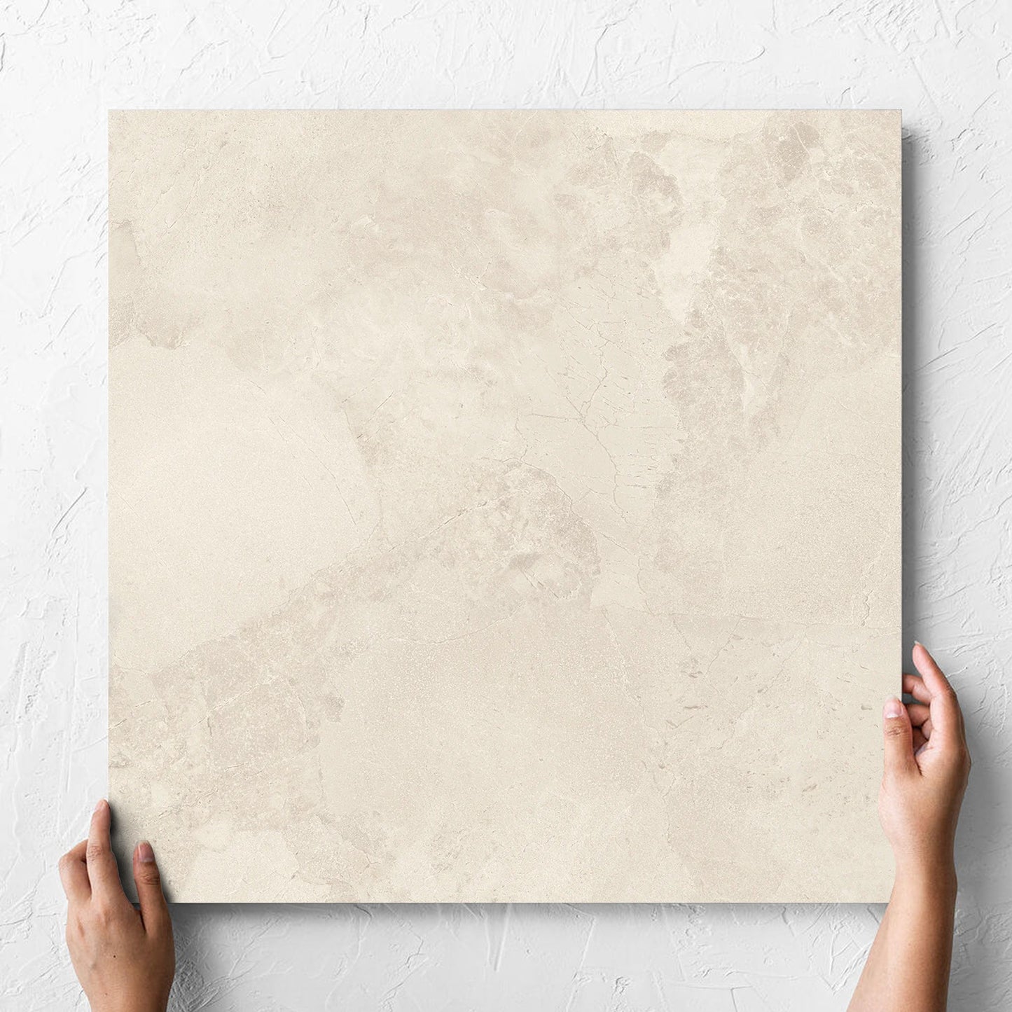 Hand holding a single Aurelia Stone White Matt 600x600mm tile against a white rendered wall, showing the matt surface