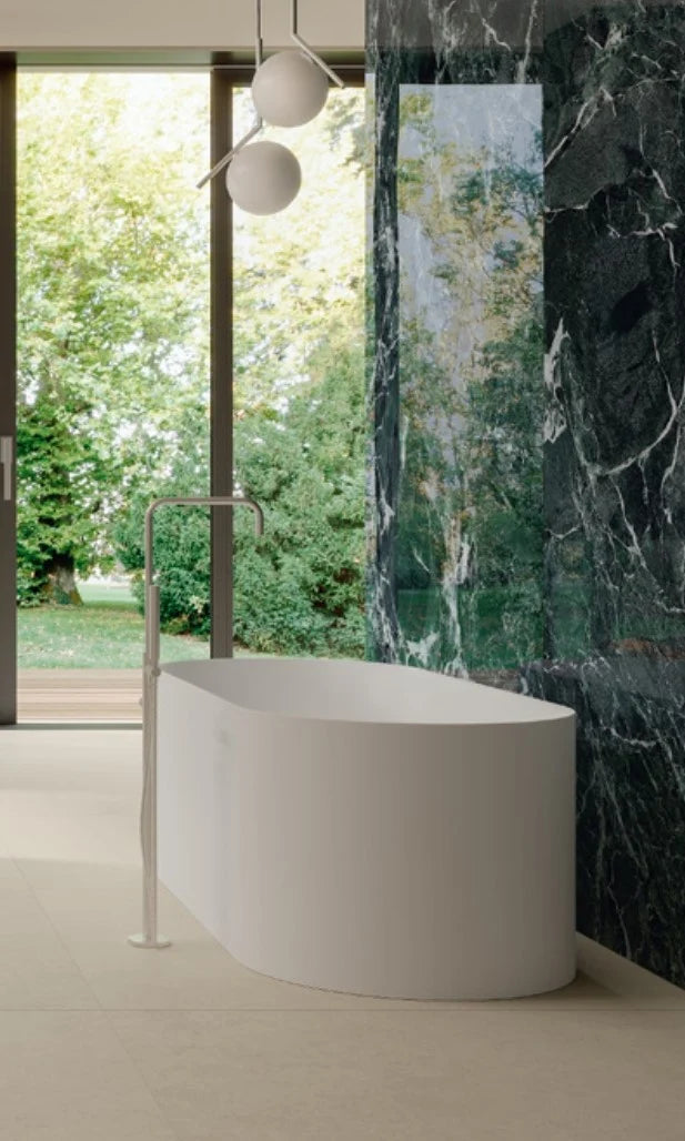 Balance Ivory Matt 600x1200mm porcelain tile on a spacious bathroom floor beside a freestanding white bath, floor-mounted filler, and dark green marble feature wall.