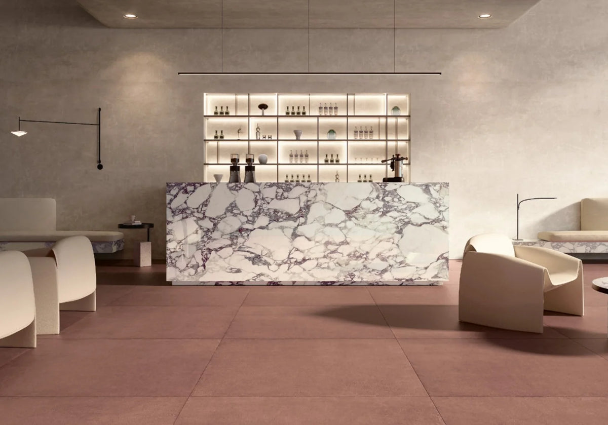 Balance Marsala Red 600x600mm tiles laid across a contemporary lounge bar floor, complementing cream curved armchairs and a Calacatta marble reception desk.