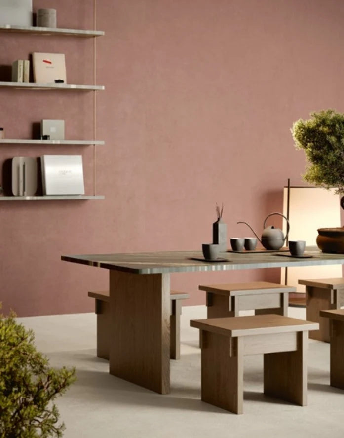 Balance Marsala Red 600x600mm tiles on a warm dusty-rose dining room wall, paired with a minimalist wooden table, bench seating, and a bonsai tree.
