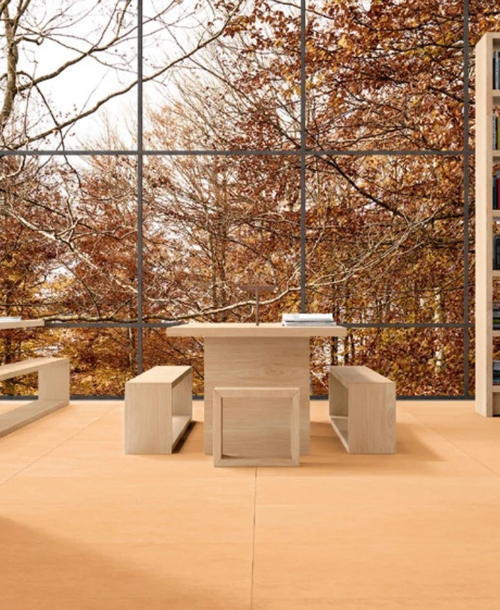 Balance Orange Matt 600x600mm floor tiles installed in a minimalist library dining area with light wood furniture and floor-to-ceiling autumn forest views.