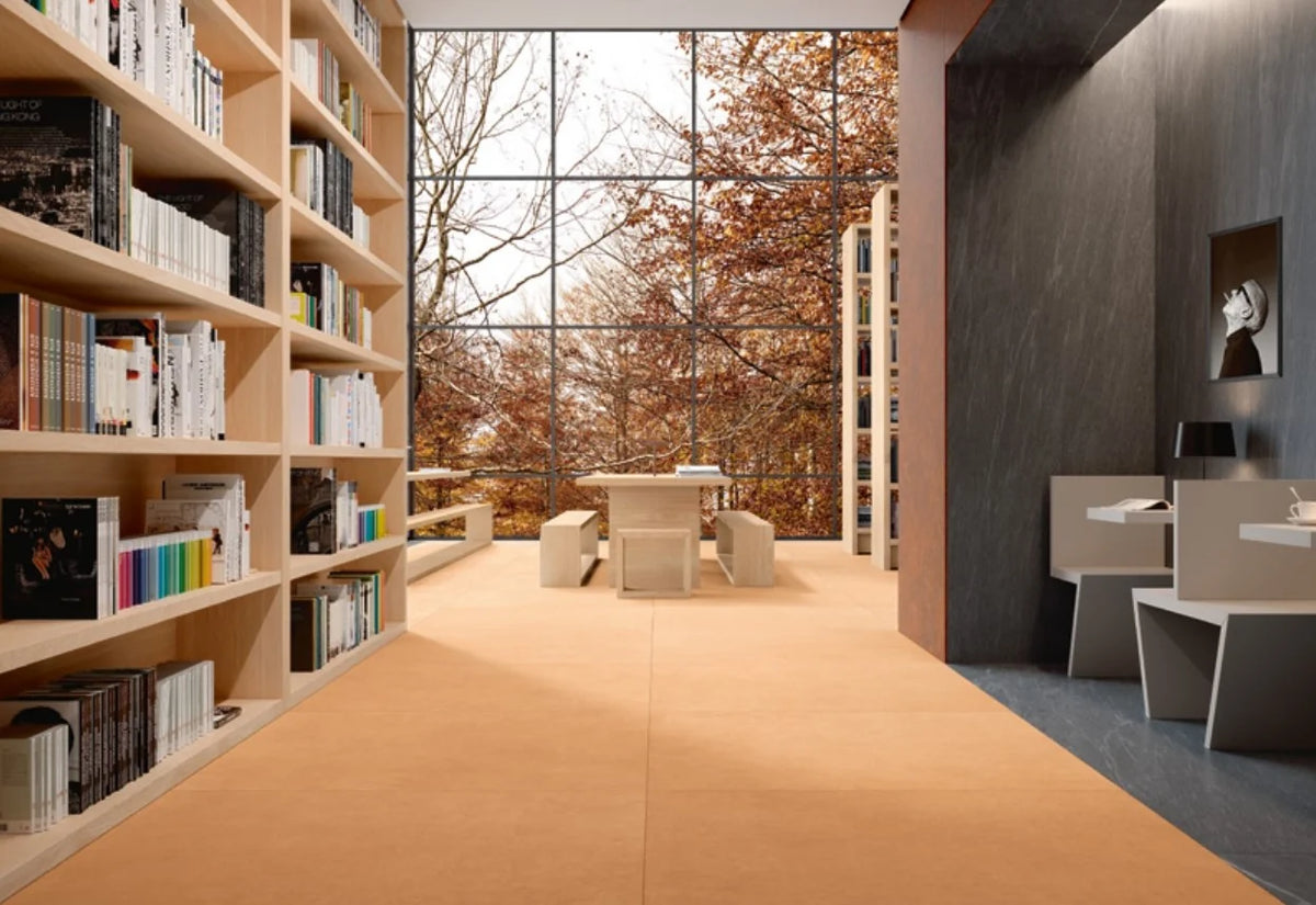Balance Orange Matt 600x600mm tiles installed in a modern library reading room with floor-to-ceiling autumn windows and built-in bookshelves.