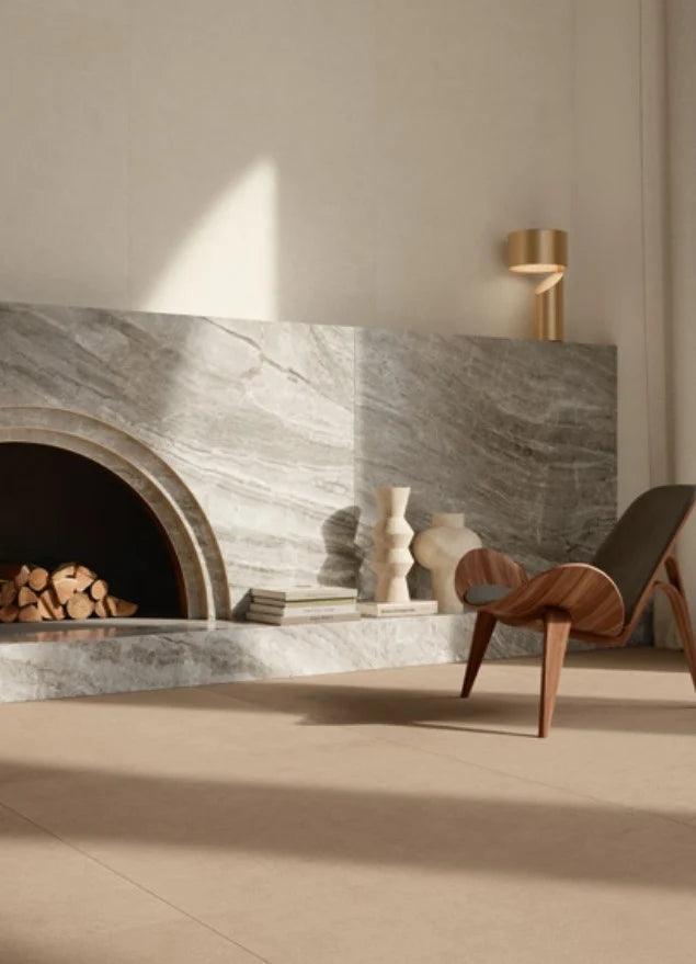 Balance Tan Matt 600x600mm tiles cladding a sculptural arched marble-effect fireplace surround in a minimalist living room with a walnut lounge chair.