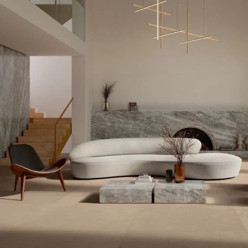 Balance Tan Matt 600x600mm floor tiles in a modern living room featuring a curved sofa, marble fireplace surround, and gold pendant lighting.