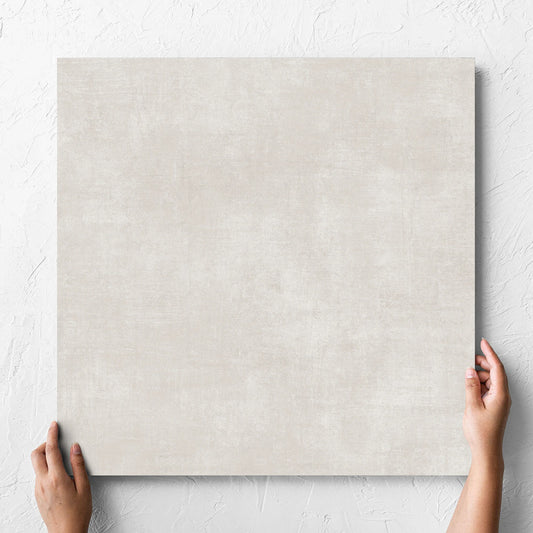 Hand holding a single Bayside Champagne Natural Matt 600x600mm tile against a white rendered wall, showing the matt surface
