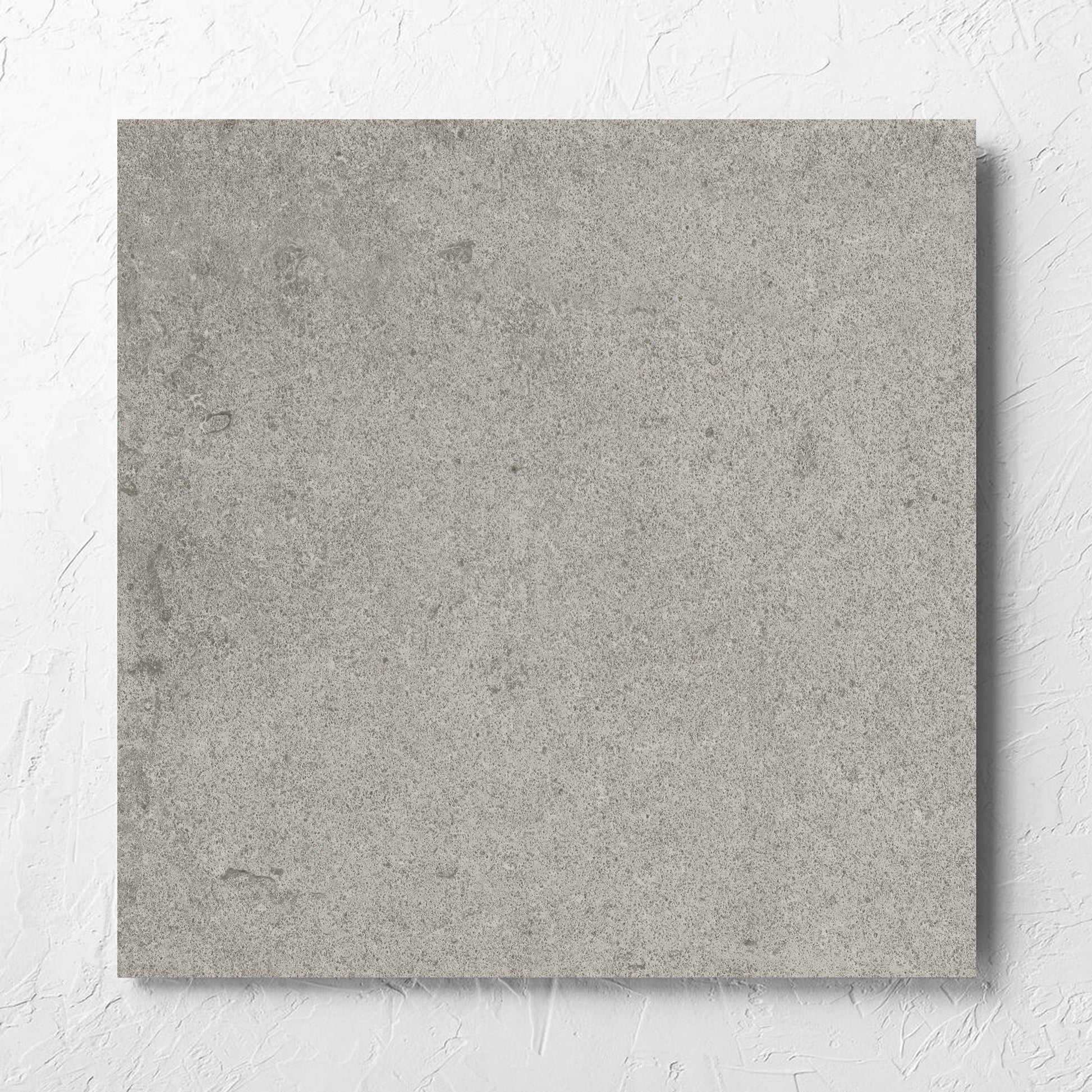 Beachstone Grey Grip 600x600x20mm tile laid flat on a white rendered wall, showing the matt surface