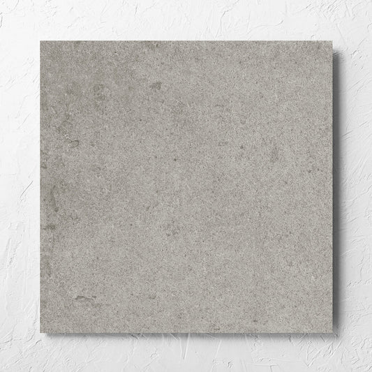 Beachstone Grey Grip 600x600x20mm tile laid flat on a white rendered wall, showing the matt surface