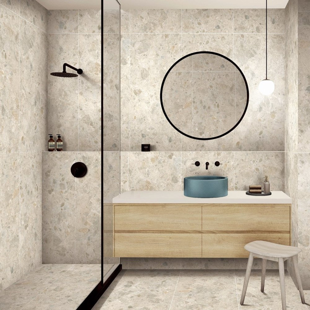 Bedrock Ivory Matt 600x600mm terrazzo-effect tiles covering walls and floor of a modern bathroom featuring a timber vanity, round mirror, and walk-in shower.