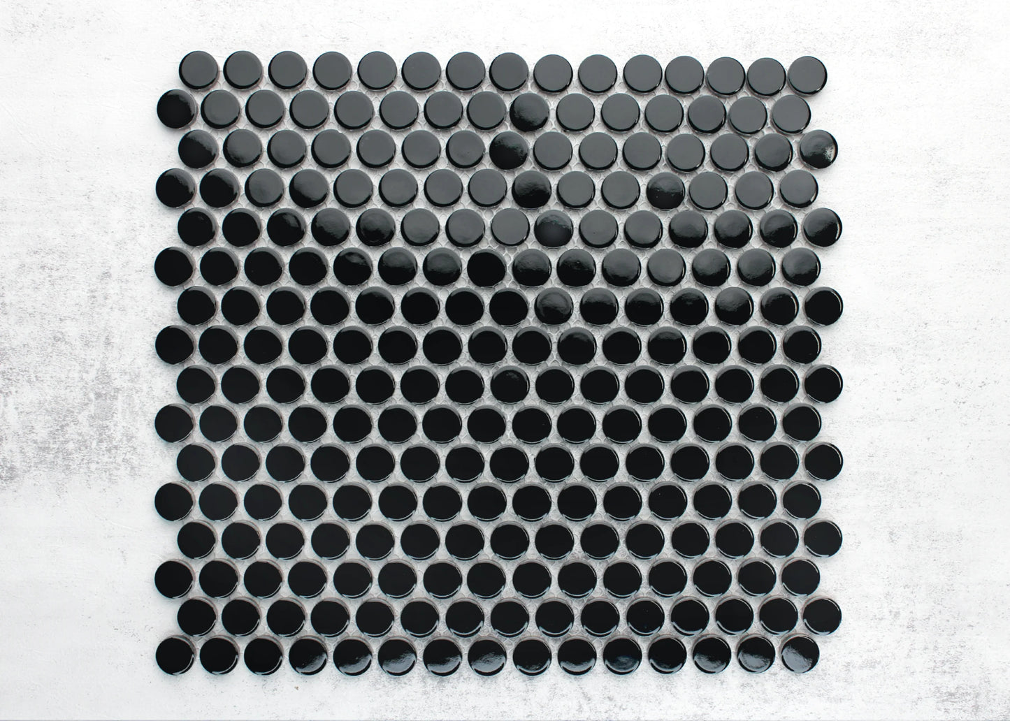 Close-up pack shot of Black Gloss Diameter Glazed Porcelain Penny Round 19mm tiles arranged in a grid pattern showing glossy circular black mosaic pieces with grey grout joints on a white background.
