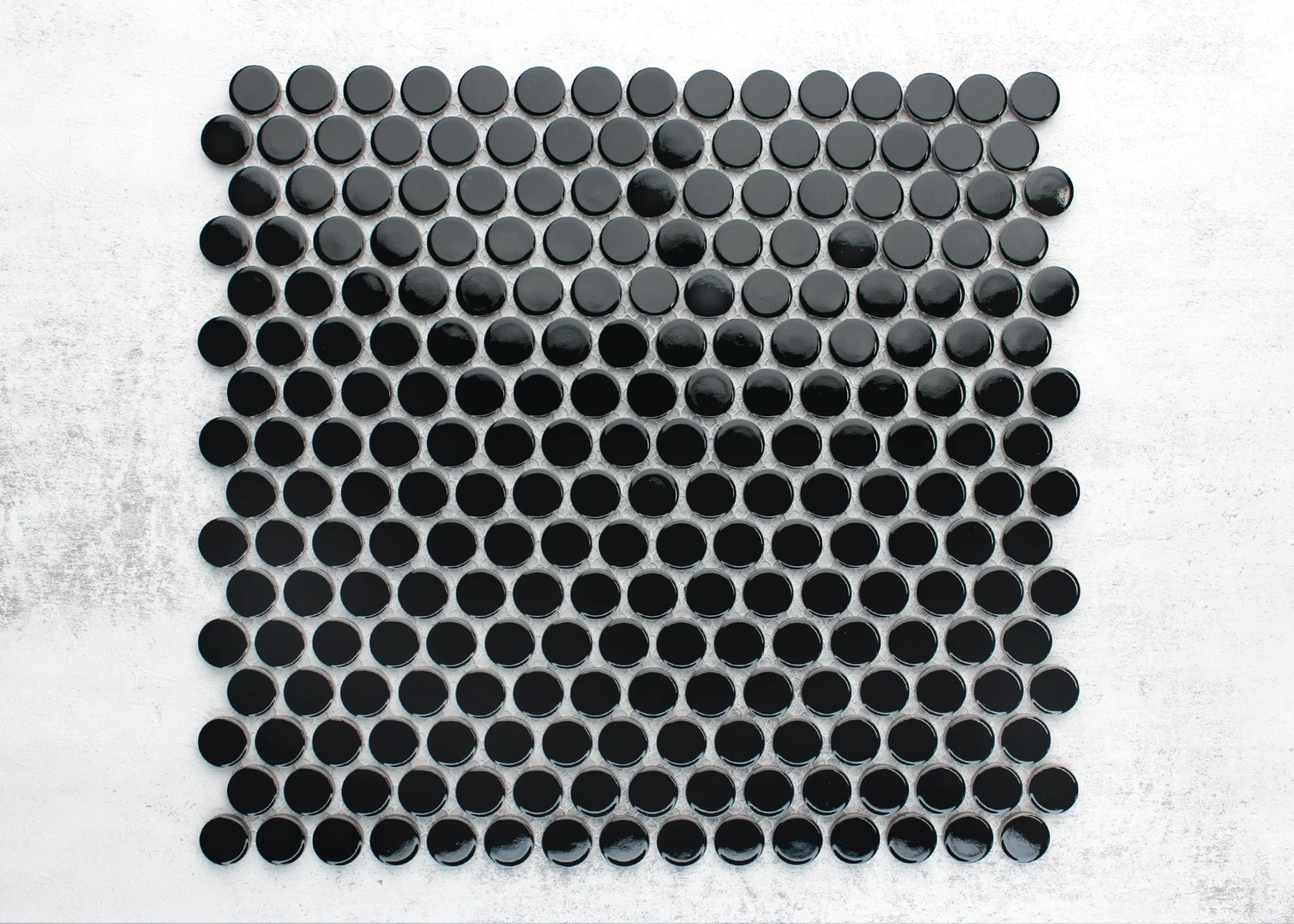 Close-up pack shot of Black Gloss Diameter Glazed Porcelain Penny Round 19mm tiles arranged in a grid pattern showing glossy circular black mosaic pieces with grey grout joints on a white background.