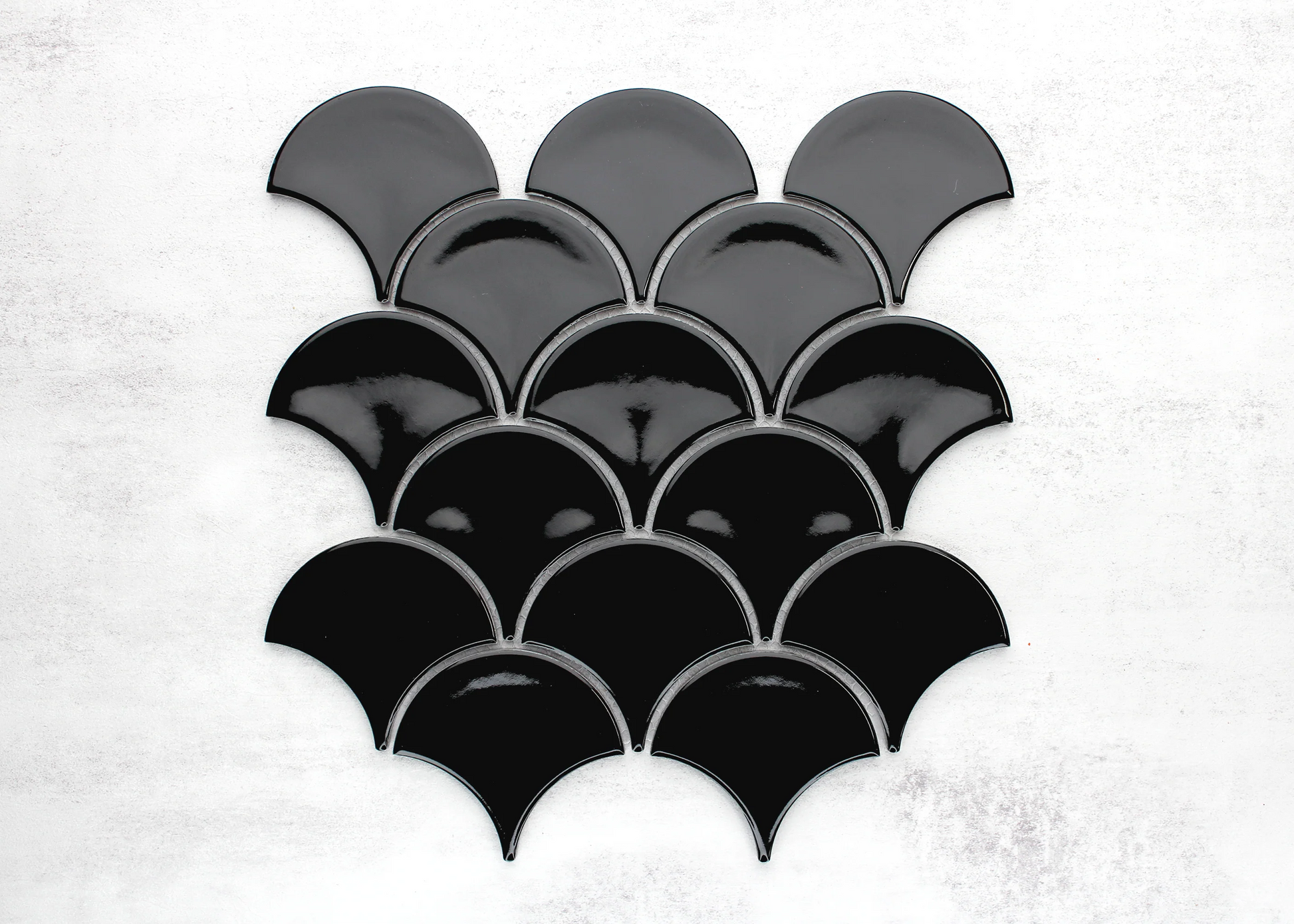 Pack shot of Black Gloss Glazed Porcelain Fishscale 95x87mm tiles arranged in an overlapping scale pattern with a high-gloss finish.