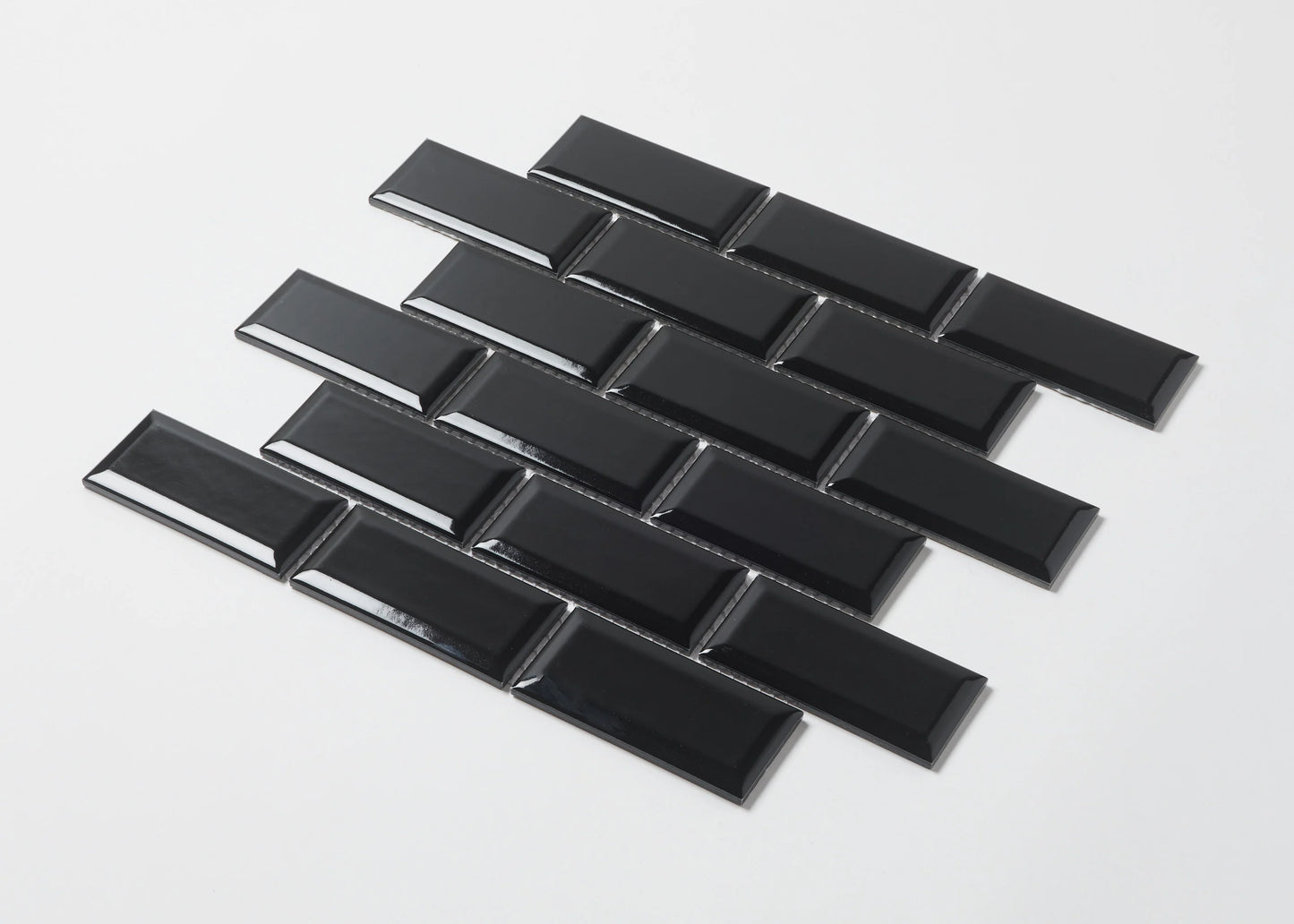 Pack shot of Black Gloss Glazed Porcelain Rectangle Bevelled Edge 45x95mm tiles arranged in a staggered brick pattern showing their high-gloss finish and bevelled profile.