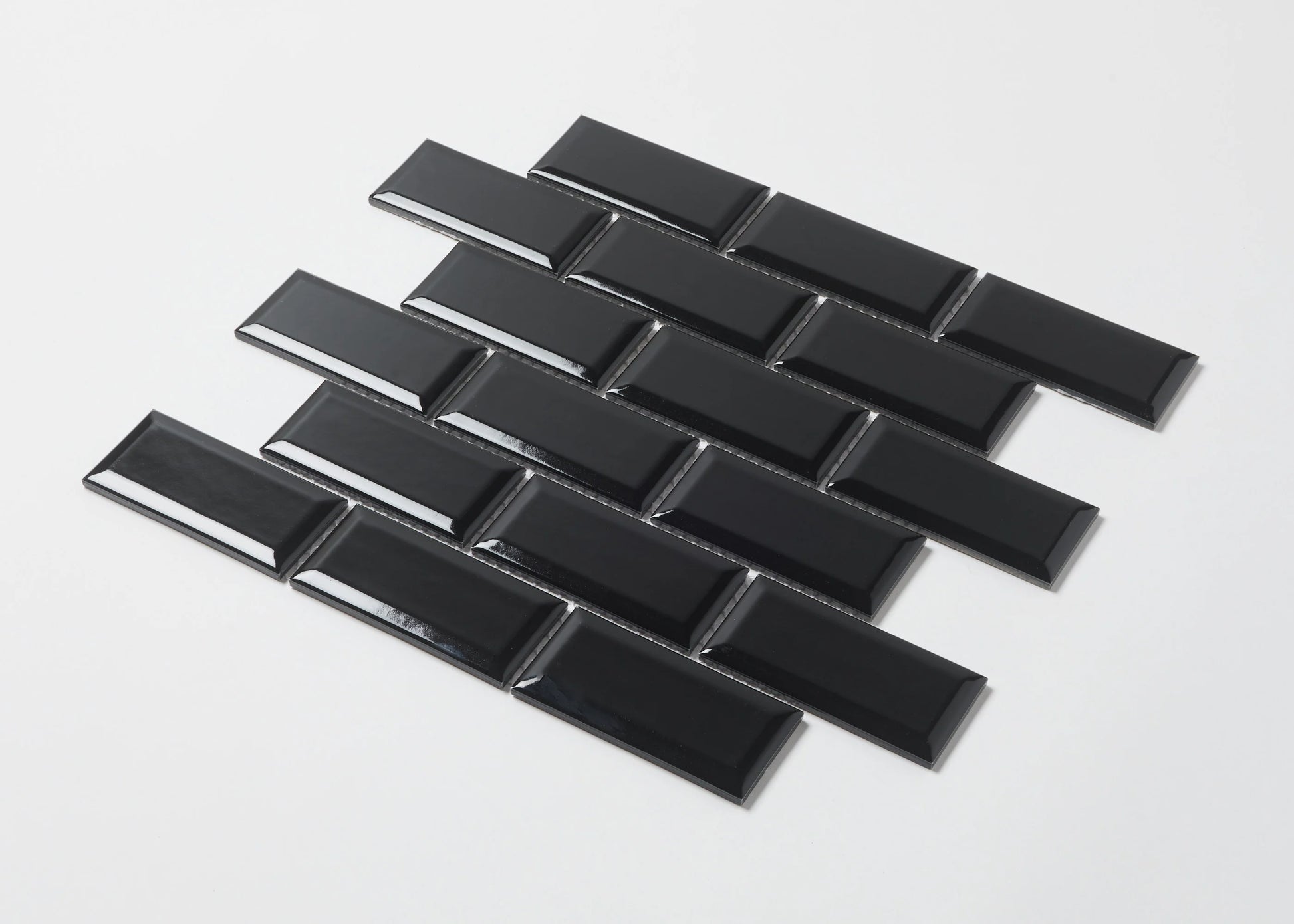 Pack shot of Black Gloss Glazed Porcelain Rectangle Bevelled Edge 45x95mm tiles arranged in a staggered brick pattern showing their high-gloss finish and bevelled profile.