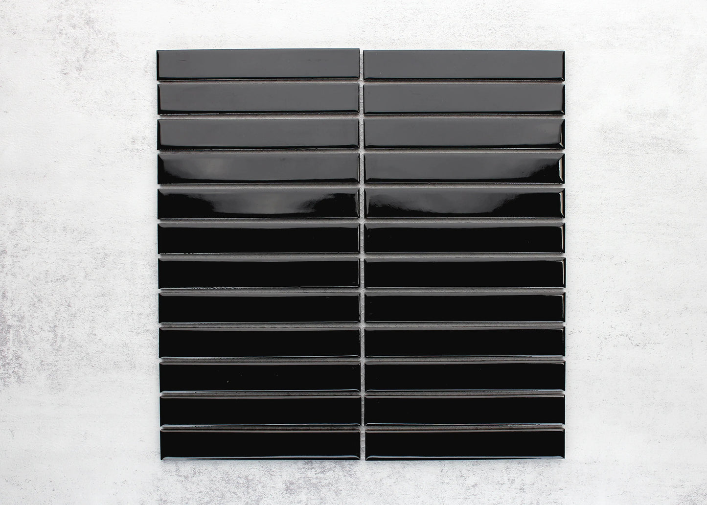Flat lay pack shot of Black Gloss KitKat Straight Bone Pattern 22x145mm tiles arranged in two stacked columns showing their glossy finish and elongated rectangular shape.