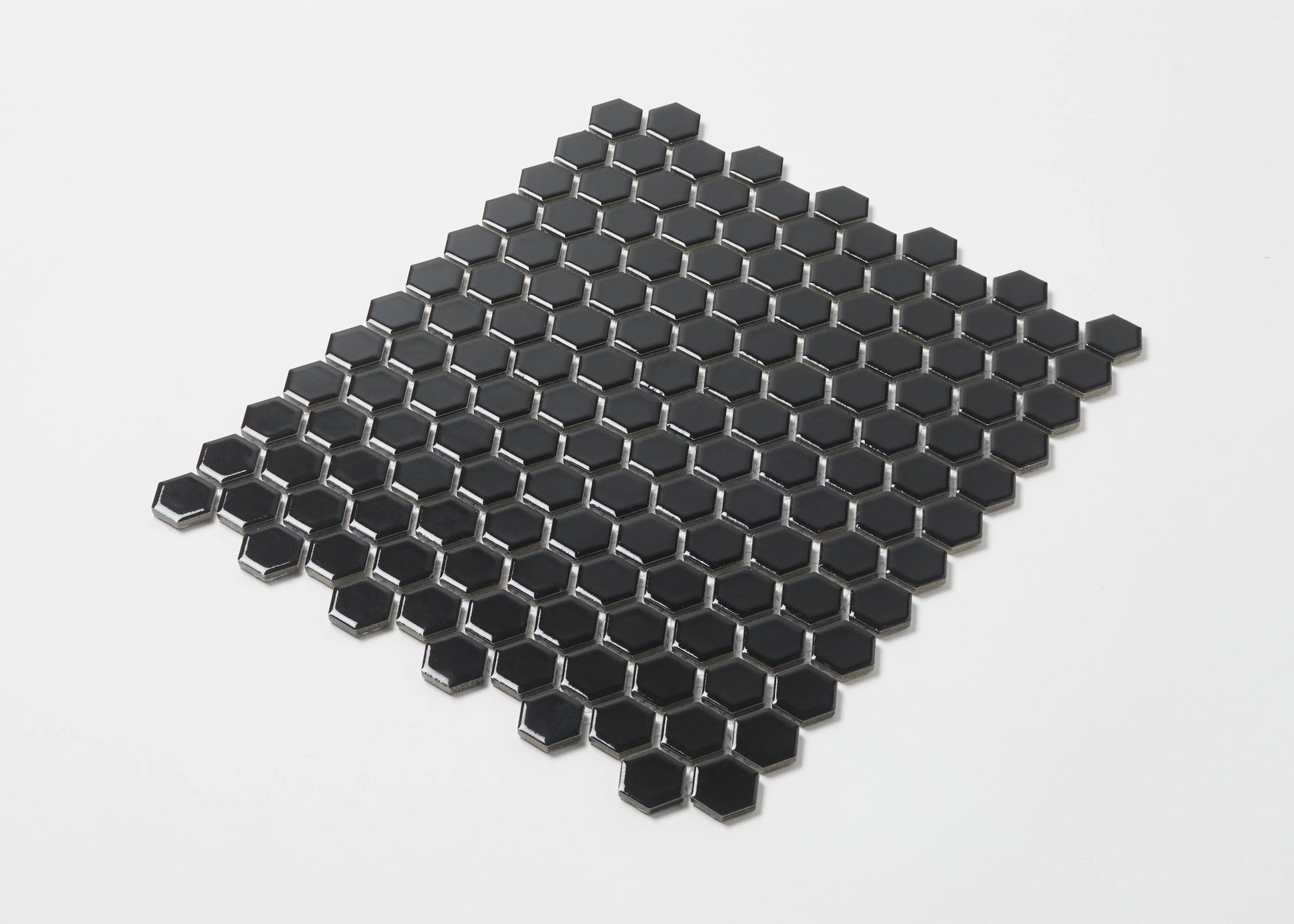 Pack shot of Black Gloss Porcelain Glazed Hexagon 23mm mosaic tile sheet showing a uniform grid of small glossy black hexagonal tiles on mesh backing.