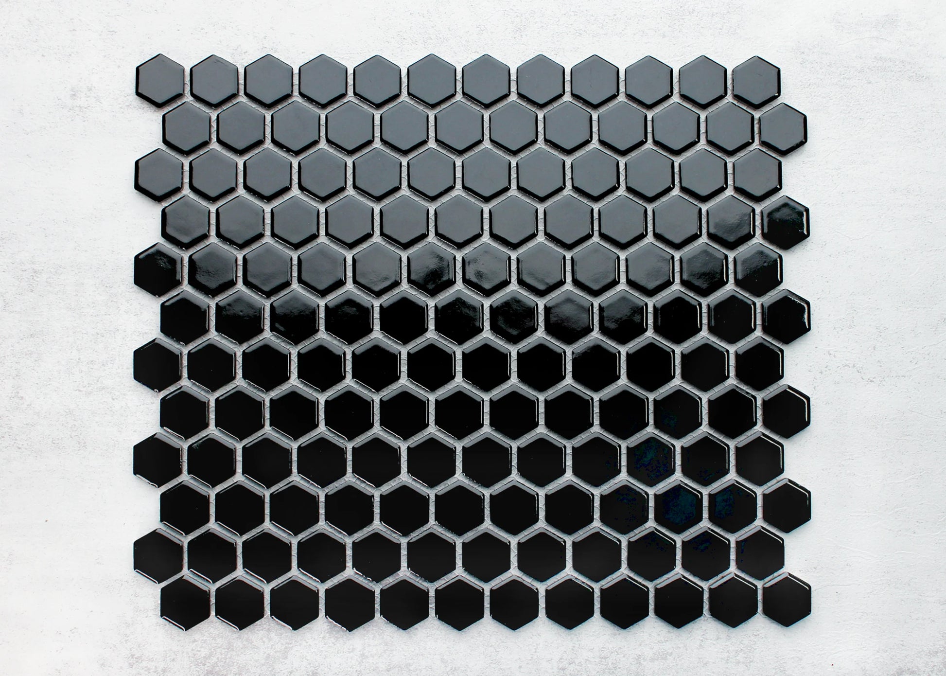 Black Gloss Porcelain Glazed Hexagon 23mm mosaic sheet displayed flat, showing a gradient from dark grey to deep gloss black small hexagonal tiles.