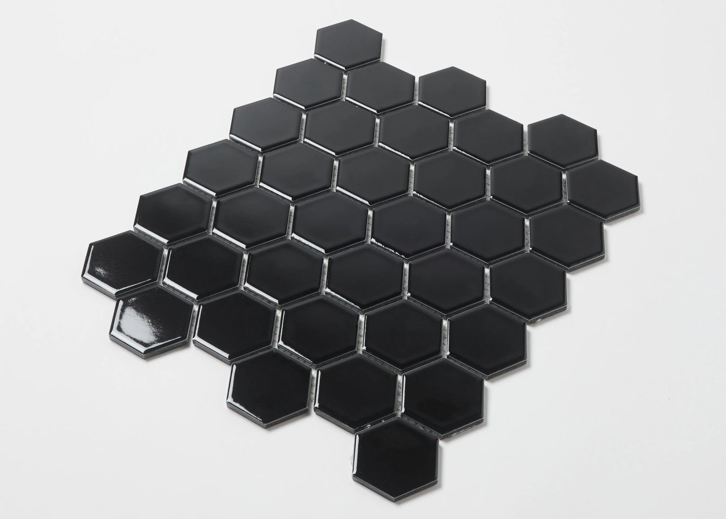Pack shot of Black Gloss Porcelain Glazed Hexagon 51x59mm tiles arranged in a honeycomb mosaic sheet pattern against a white background.