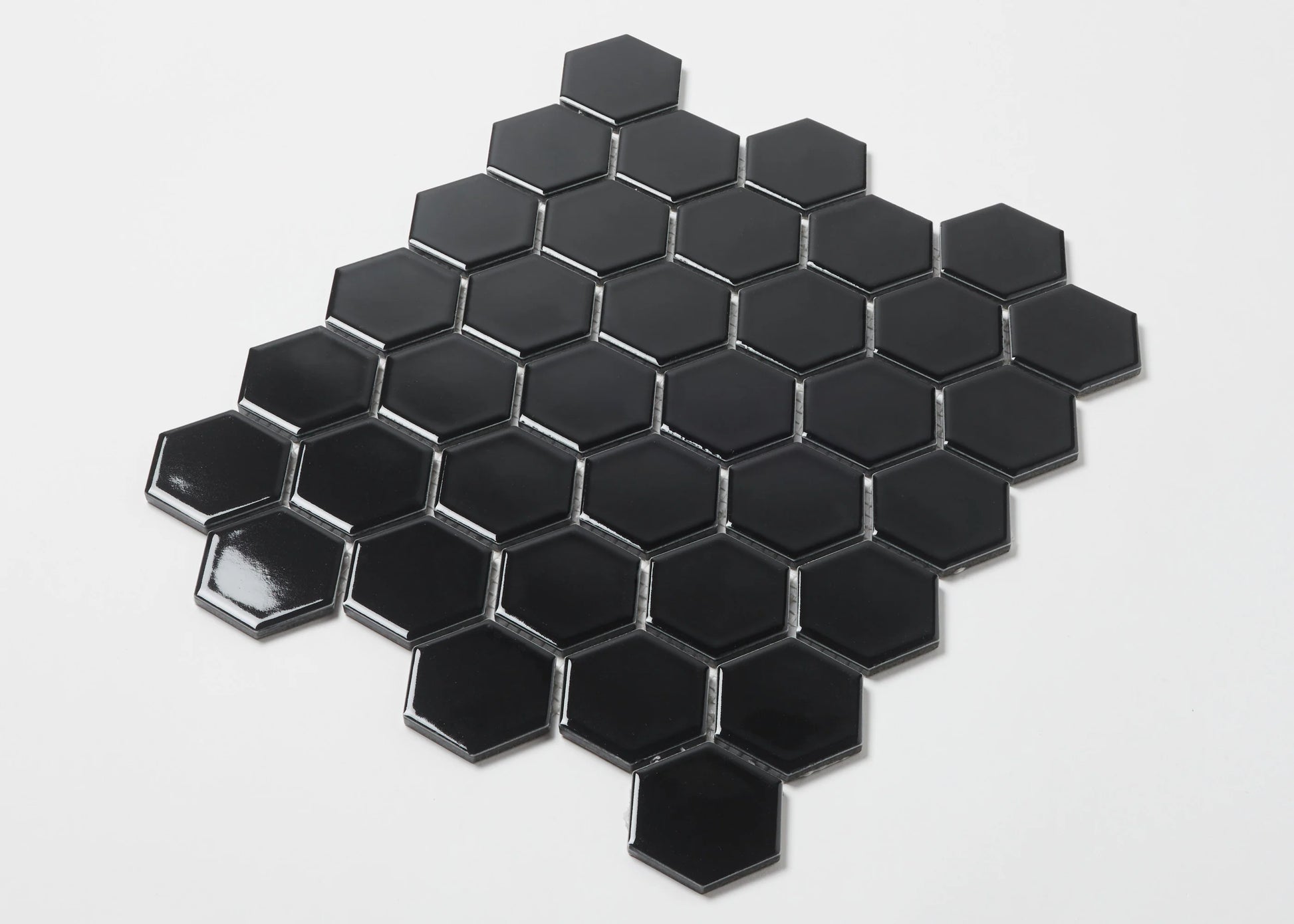 Pack shot of Black Gloss Porcelain Glazed Hexagon 51x59mm tiles arranged in a honeycomb mosaic sheet pattern against a white background.
