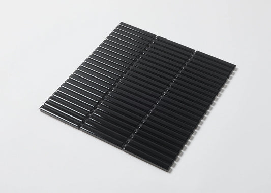 Pack shot of Black Gloss Porcelain Glazed KitKat 12x92mm tiles arranged in a flat lay showing glossy black finger-shaped mosaic strips on mesh backing.