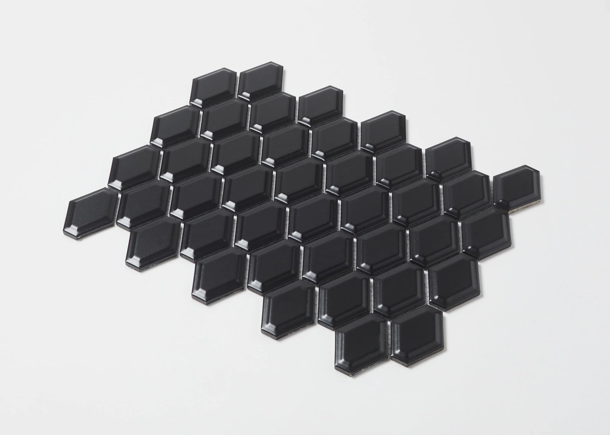 Pack shot of Black Matte External Porcelain Glazed Honeycombe 46.5x60mm tiles arranged in a diamond cluster, showcasing their bevelled edges and matte black finish.