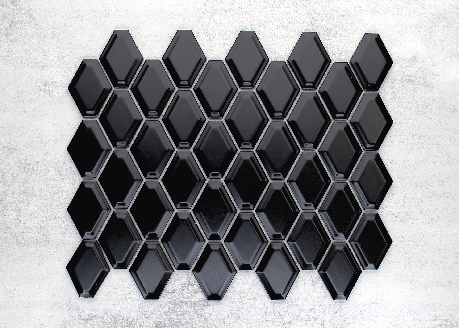 Close-up of Black Matte External Porcelain Glazed Honeycombe 46.5x60mm tiles arranged in a full sheet, showing glossy black elongated hexagon shapes with bevelled edges and grey grout lines.