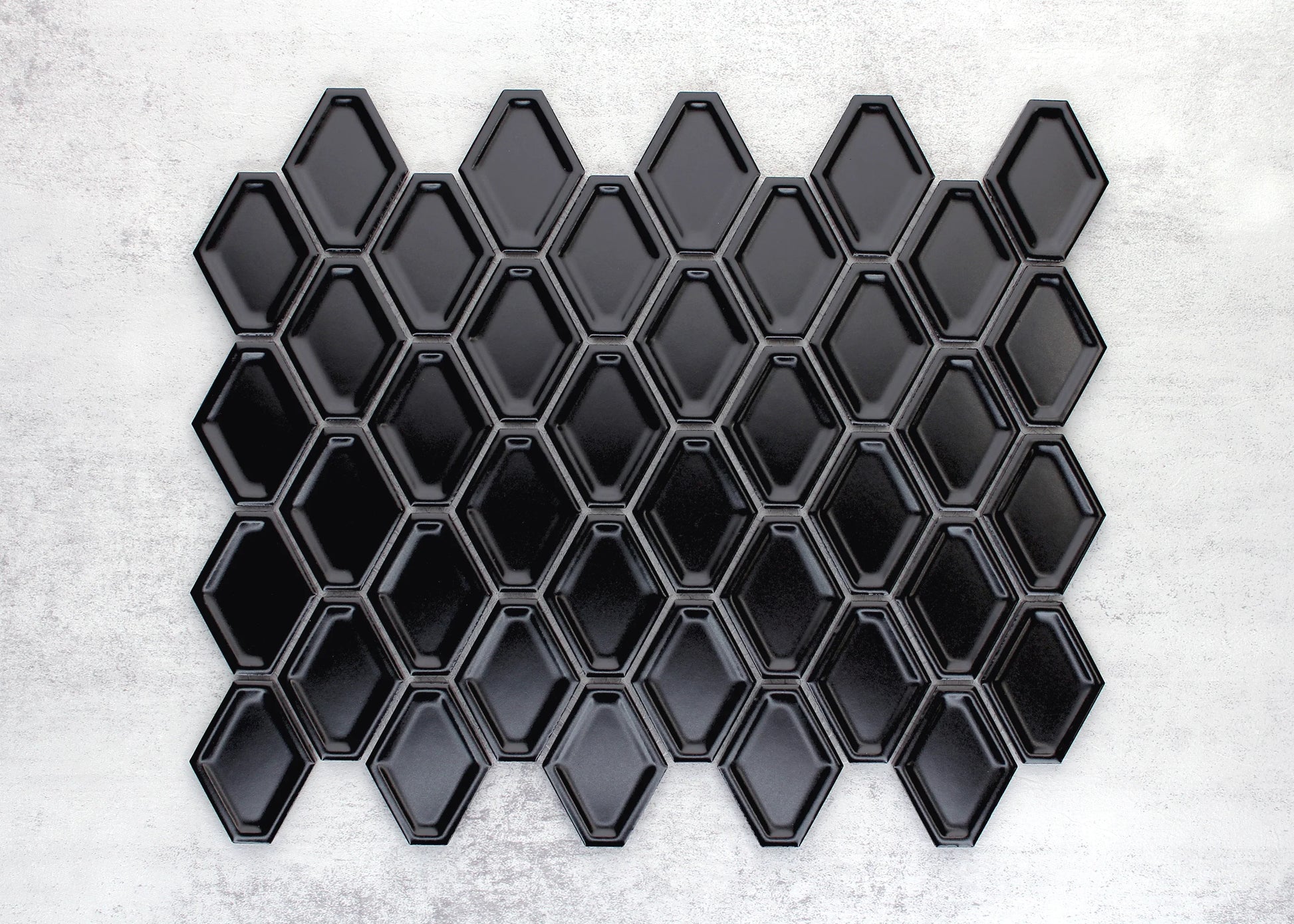 A mosaic sheet of Black Matte Internal Porcelain Glazed Honeycombe 46.5x60mm tiles showing bevelled diamond-shaped pieces in a glossy black finish arranged in an interlocking pattern.