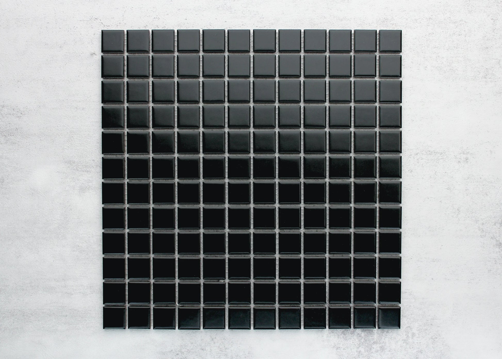 A flat lay pack shot of Black Matte Porcelain Glazed 23mm Square mosaic tiles arranged in a uniform grid sheet with grey grout lines.