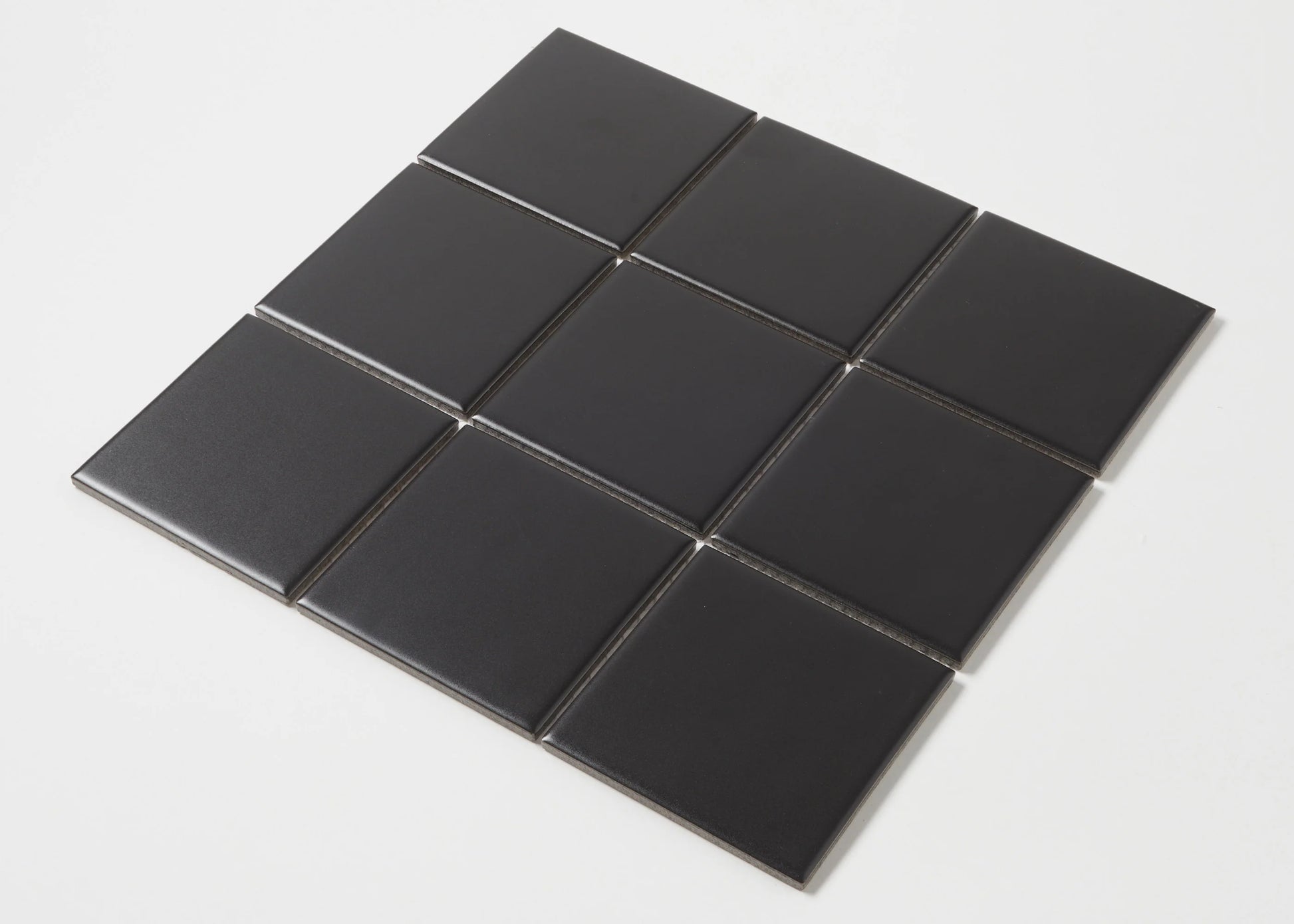 Nine Black Matte Porcelain Glazed 97x97mm Square tiles arranged in a 3x3 grid, showcasing the smooth matte black finish and square format.