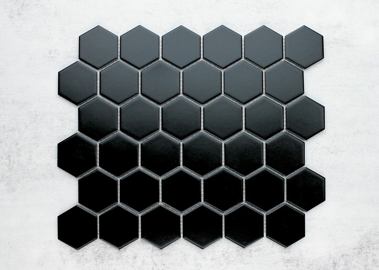Black Matte Porcelain Glazed Hexagon 51x59mm mosaic sheet displayed flat, showing a gradient from charcoal grey to deep black across individually grouted hexagonal tiles.