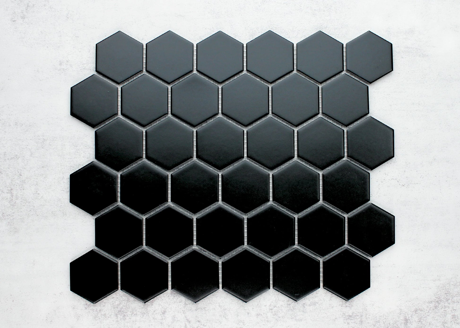 Black Matte Porcelain Glazed Hexagon 51x59mm mosaic sheet displayed flat, showing a gradient from charcoal grey to deep black across individually grouted hexagonal tiles.