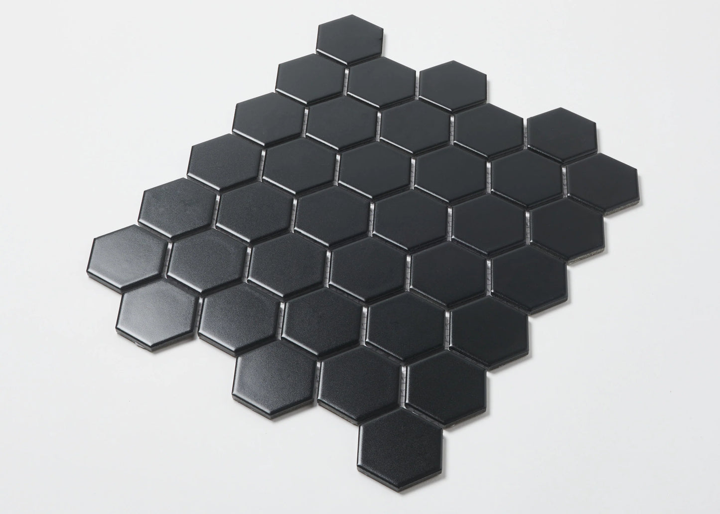 Pack shot of Black Matte Porcelain Glazed Hexagon 51x59mm tiles arranged in a diamond cluster pattern, showcasing the flat matte black finish and geometric hexagonal shape.