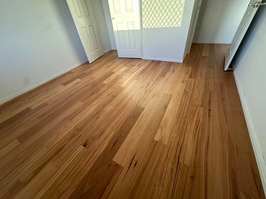 Blackbutt Engineered Australian Classic Flooring 14/3mm installed in an empty bedroom with warm honey tones, white skirting boards, and double doors opening to natural light.