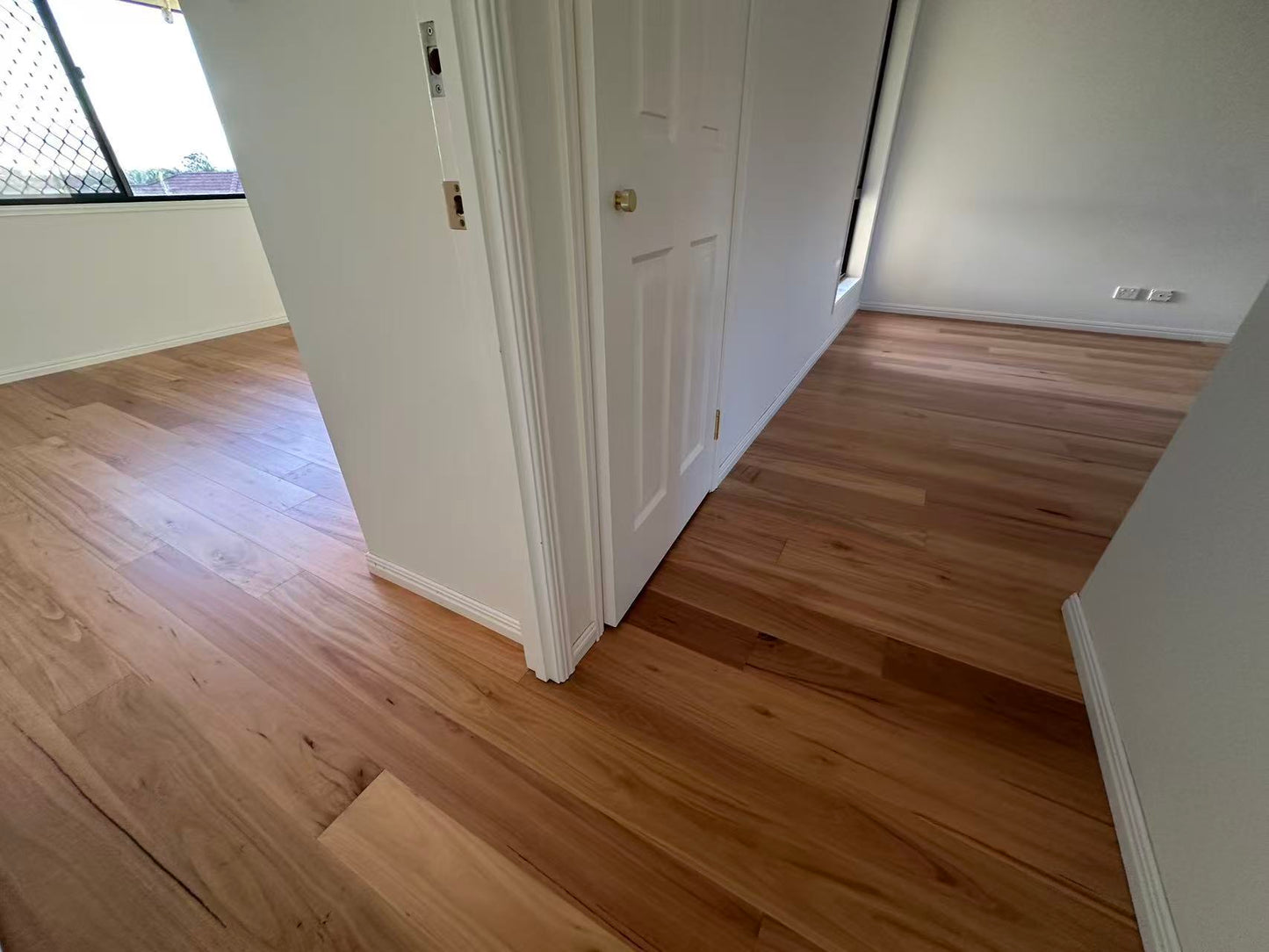 Blackbutt Engineered Australian Classic Flooring 14/3mm installed across a bright hallway and bedroom with white doors and skirting boards.