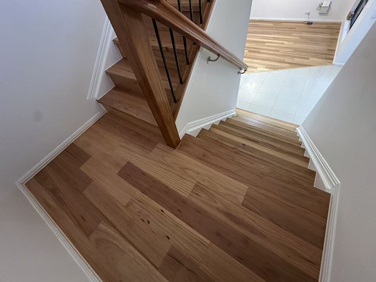 Blackbutt Engineered Australian Classic Flooring 14/3mm installed on a timber staircase and upper landing with white skirting boards and black metal balustrade balusters.
