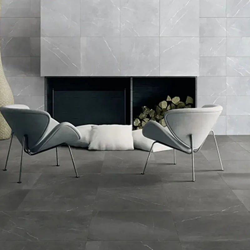 Bracca Dark Grey Lappato Rectified 600x600mm floor tiles in a contemporary living room featuring designer lounge chairs and a marble-effect tiled fireplace wall.