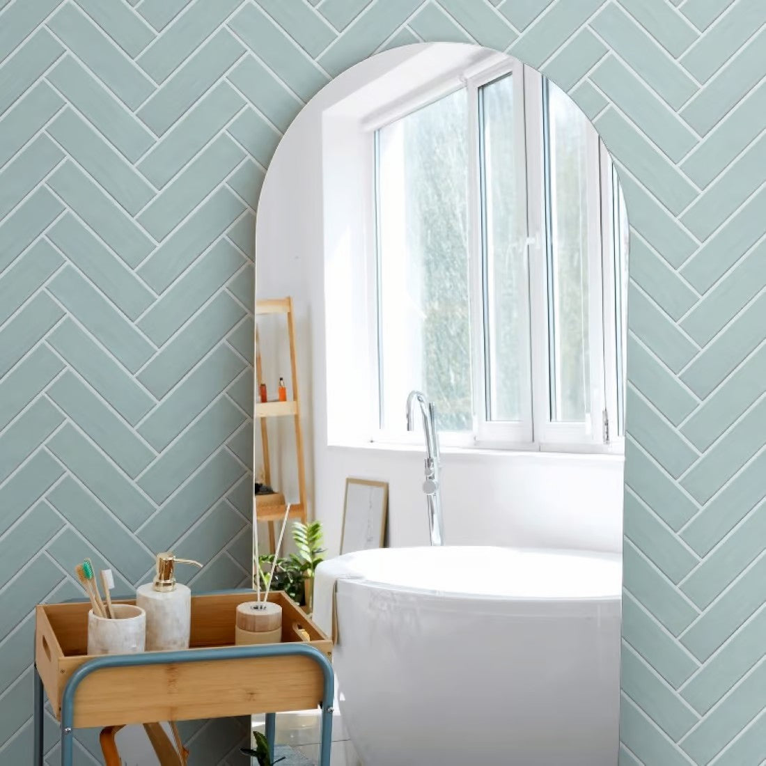 Brava Mint Satin 60x217mm tiles laid in a herringbone pattern on a bathroom wall, complementing a freestanding white bathtub and arched mirror.