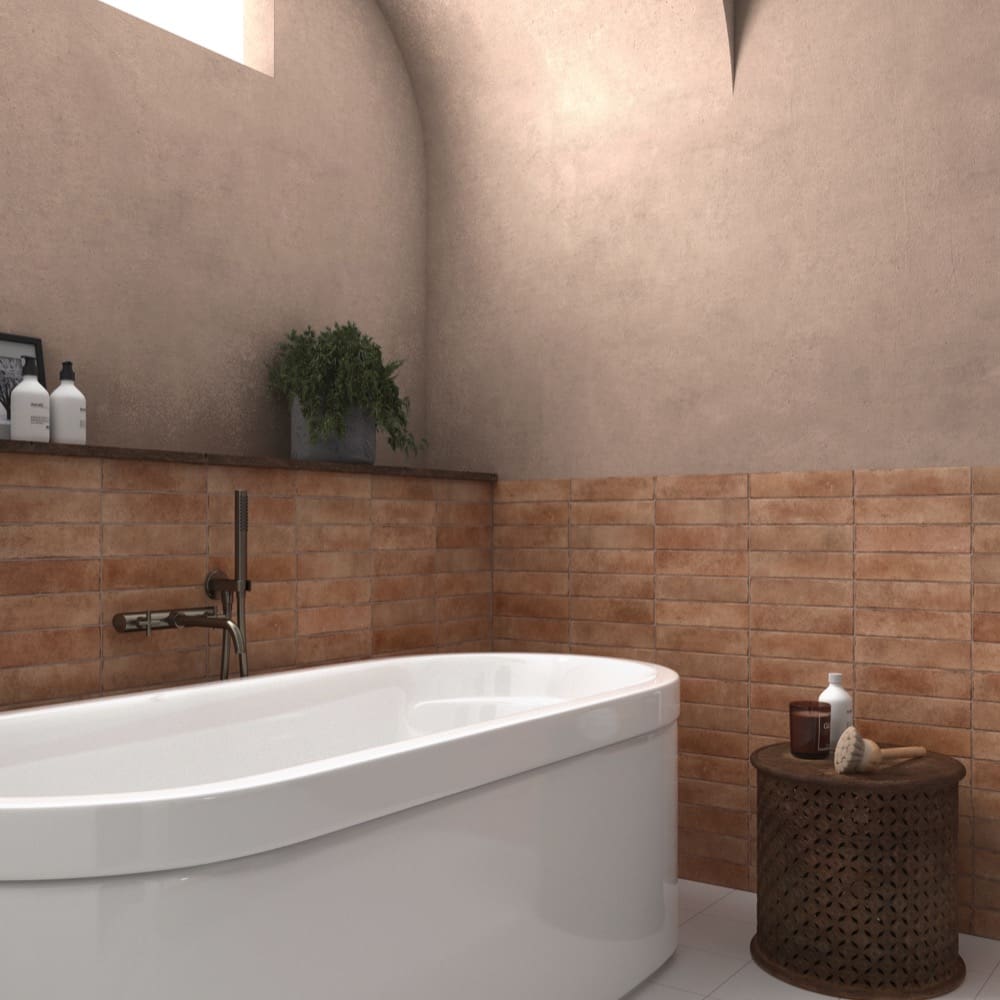 Bricks Cotto Matt 60x246mm terracotta brick tiles installed as a half-wall surround in a rustic bathroom featuring a freestanding white bathtub and decorative side table.