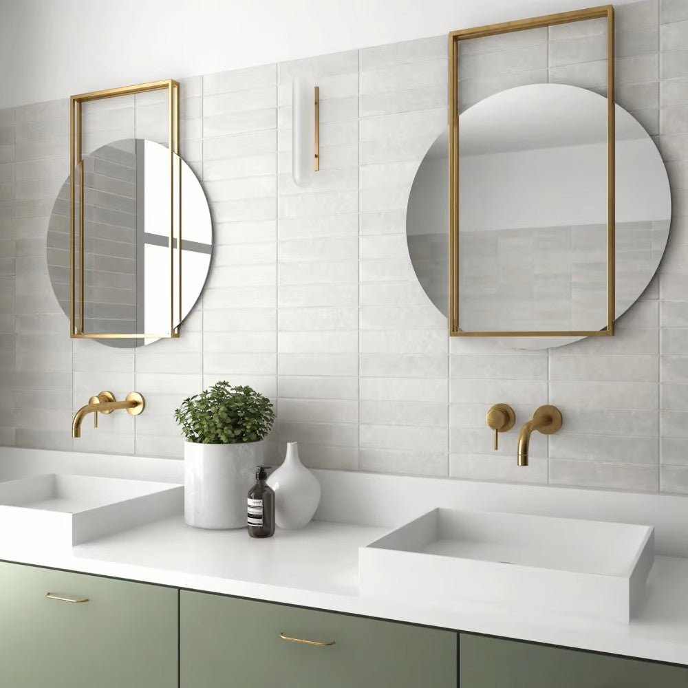 Bricks Off White Matt 60x246 wall tiles installed in a modern bathroom with green vanity cabinets, gold brass fittings, and round mirrors.